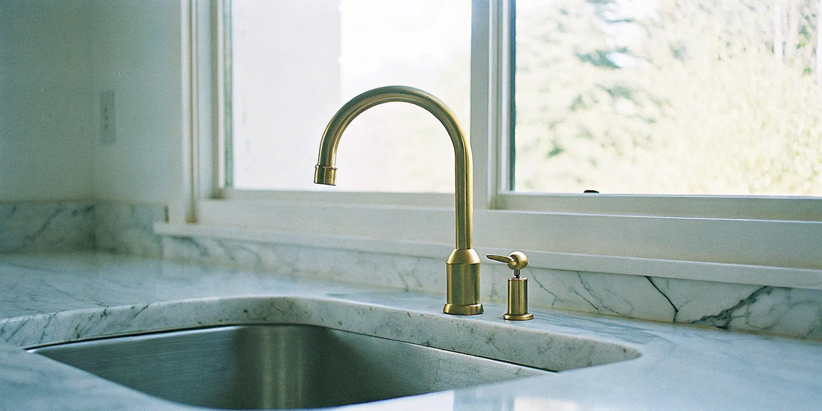 Brushed gold modern kitchen faucet with a pull-down sprayer over a kitchen sink.