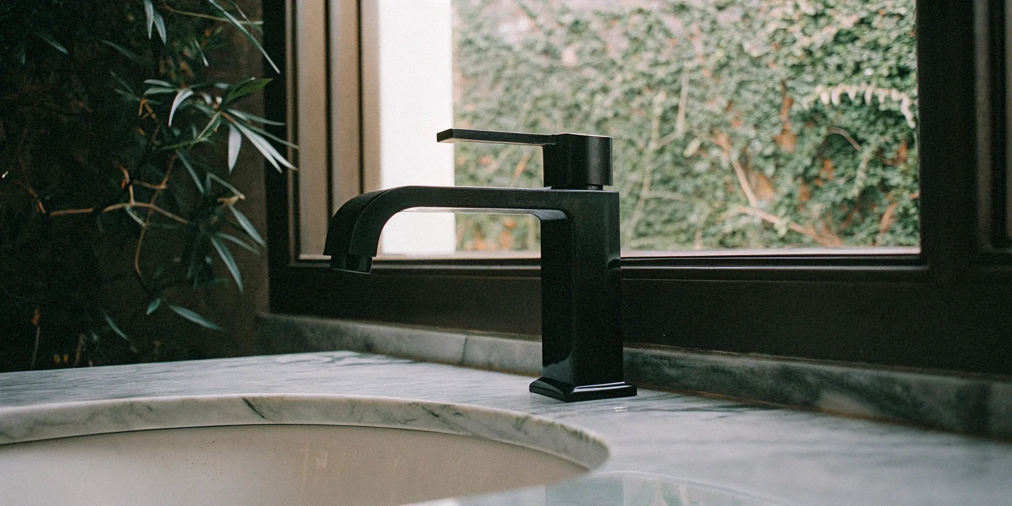 Modern black faucet on a bathroom sink with a marble countertop.