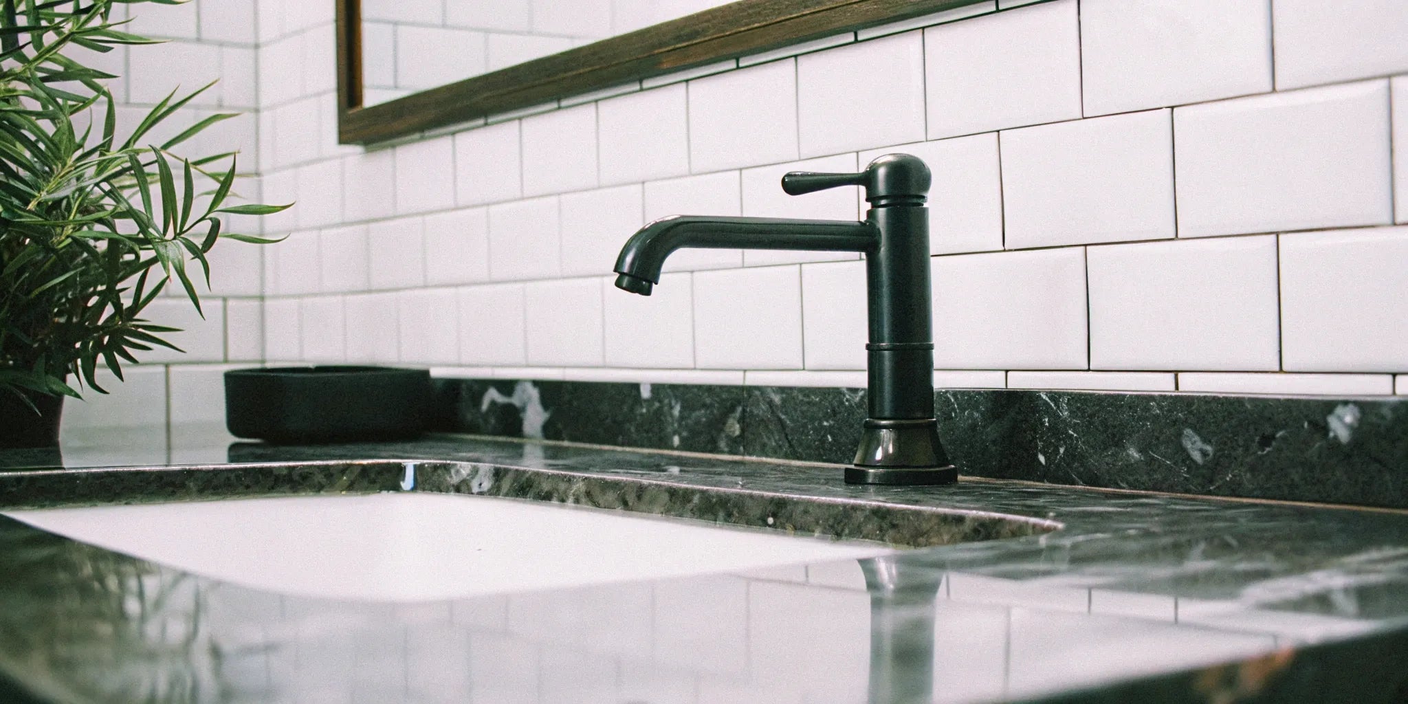 A cheap, modern black bathroom faucet installed on a white marble vanity top.