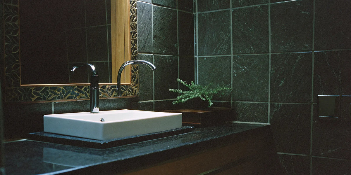 Dark porcelain slabs for walls create a seamless, modern look in this bathroom with a white sink.