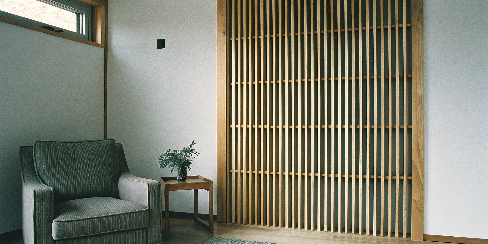 A feature wall of acoustic slat wood panels in a modern living room.