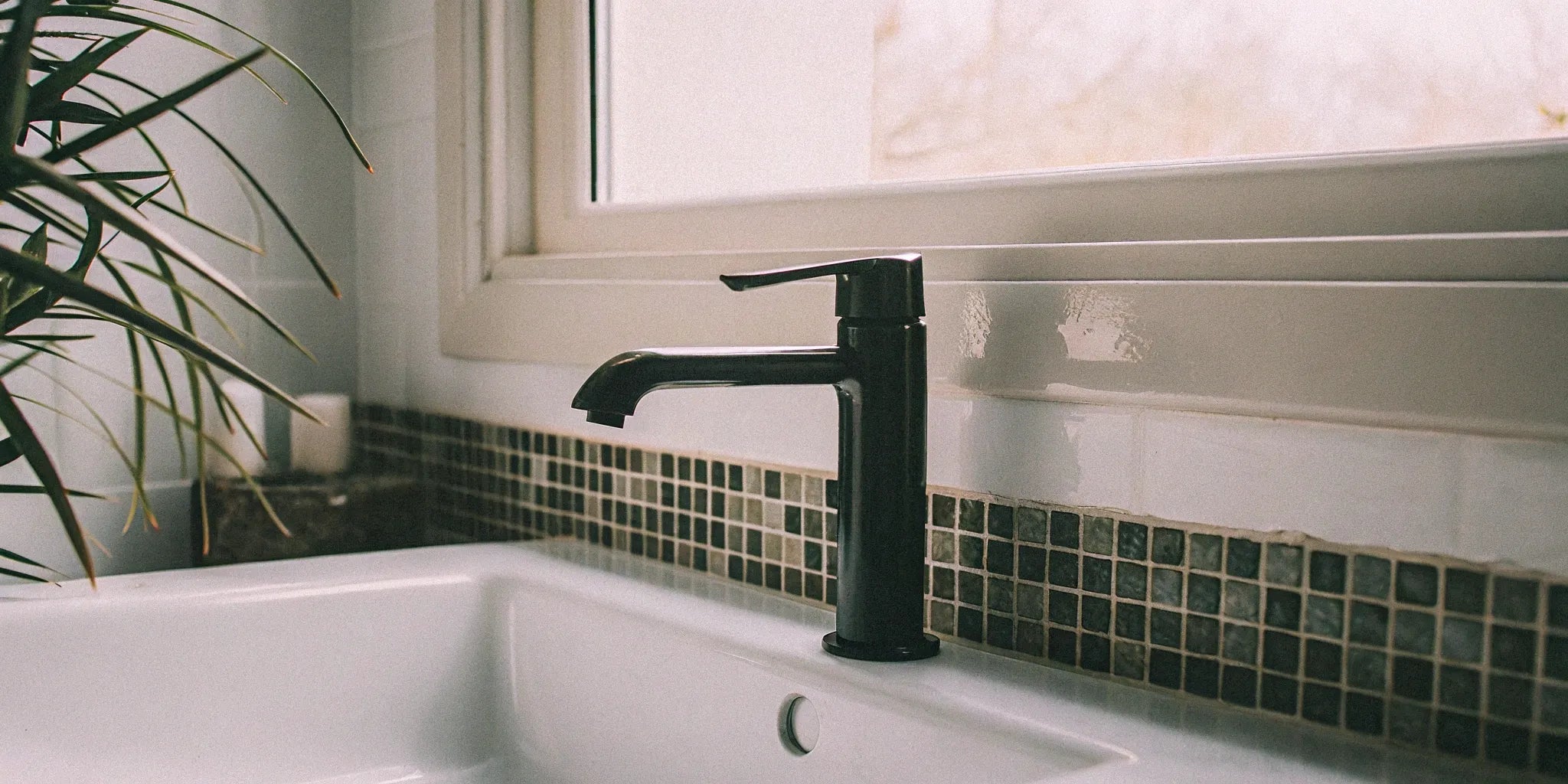 A modern black bathroom faucet on a white sink in a Union Pier bathroom.