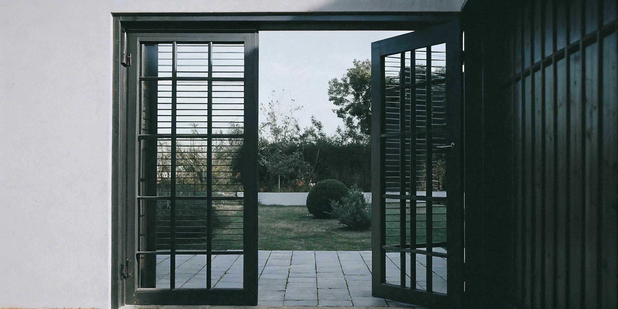 A pair of black metal exterior French doors opening to a modern home patio.