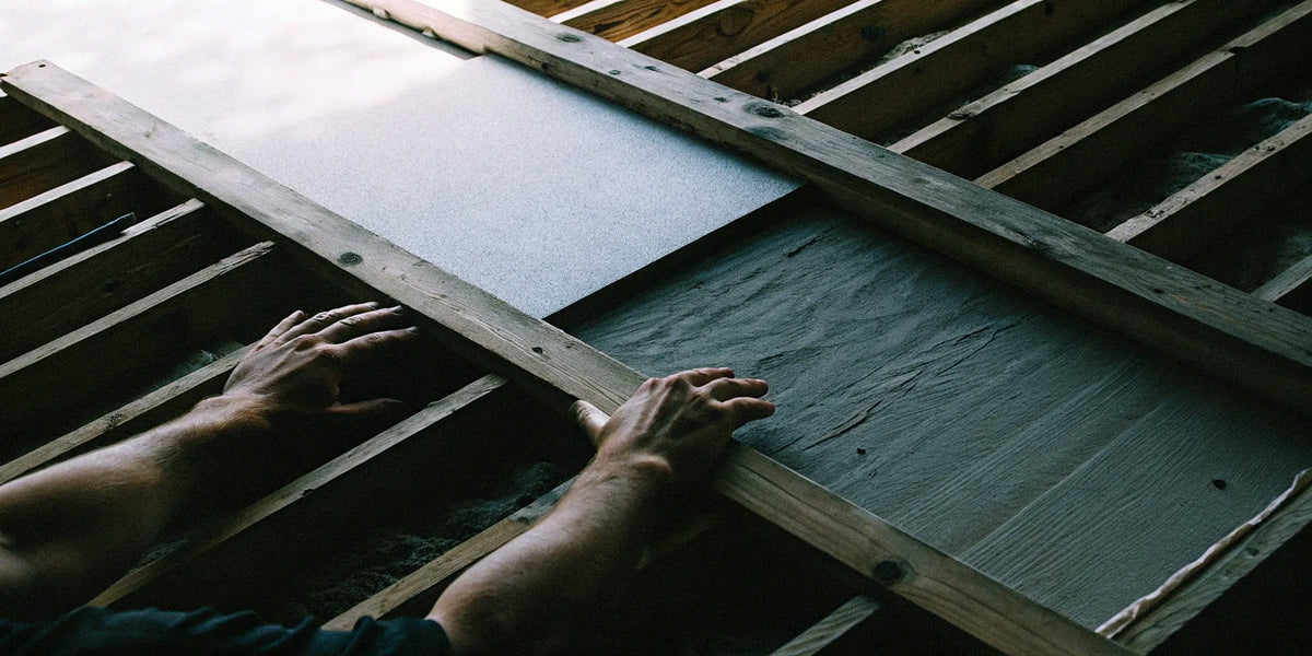 A contractor fastens fire-resistant cement boards to a wooden wall frame.