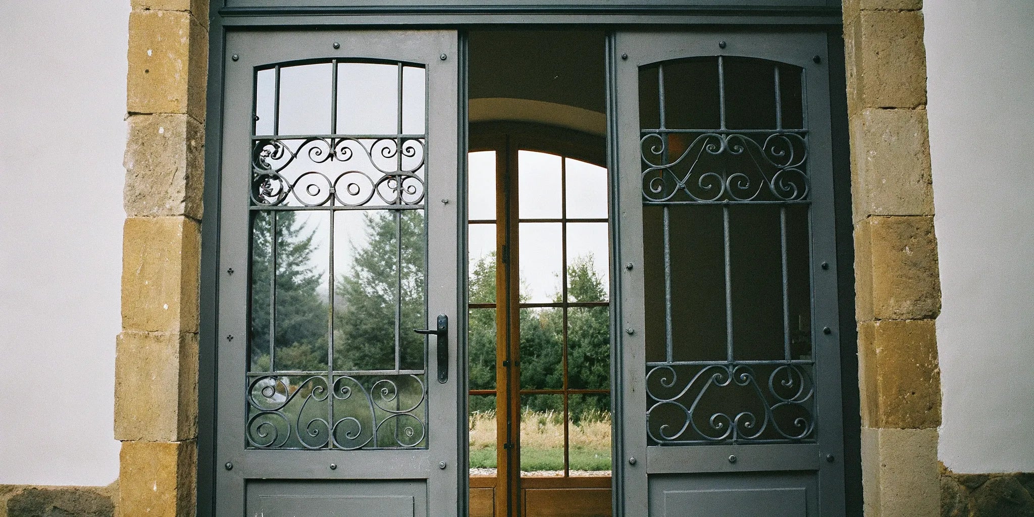 A pair of French steel exterior doors with decorative scrollwork over glass panels.