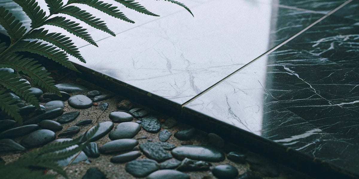 Marble-look porcelain tiles with dark pebbles and ferns.