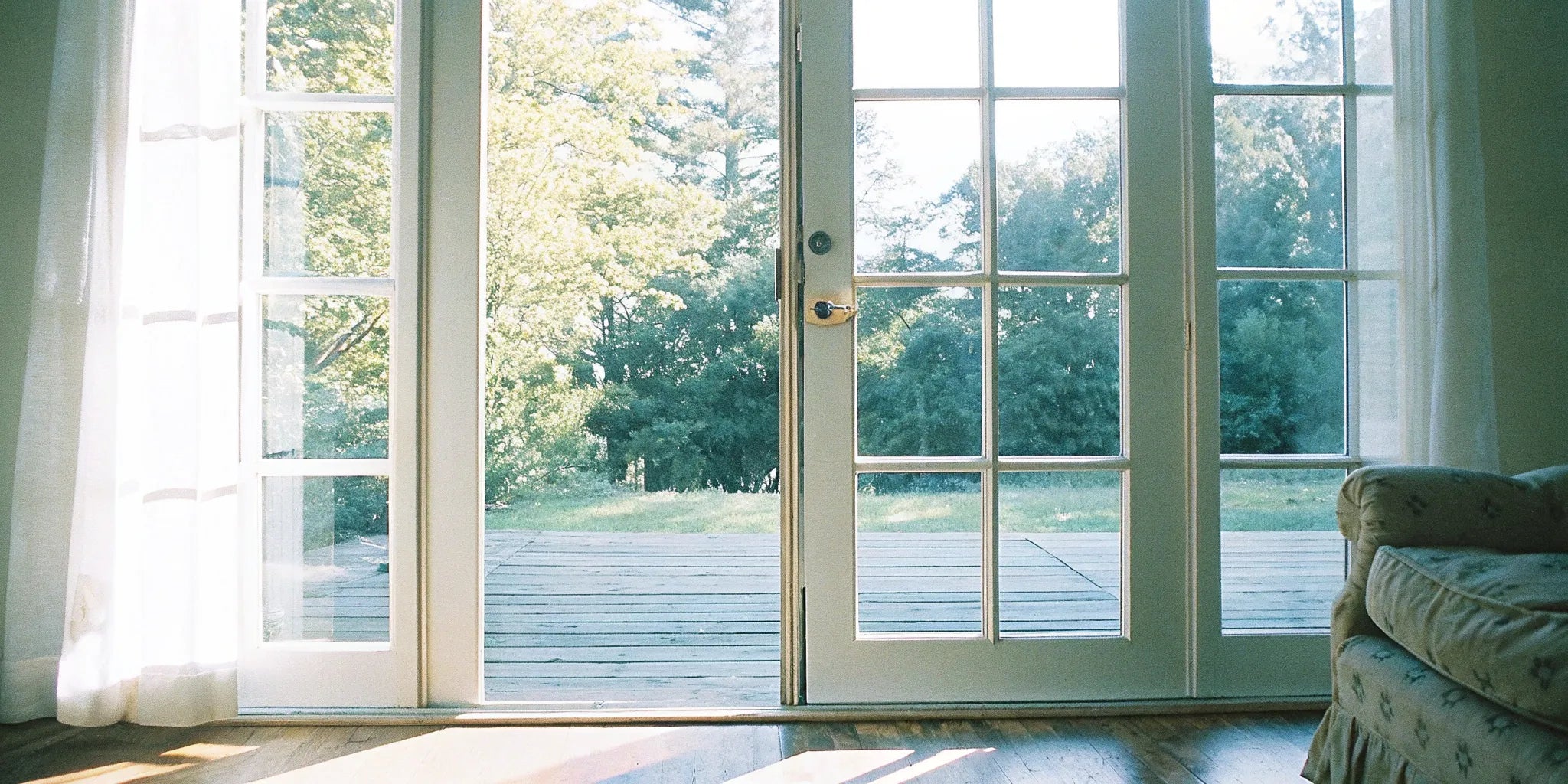Right hand outswing French door opening to a sunlit deck and garden.