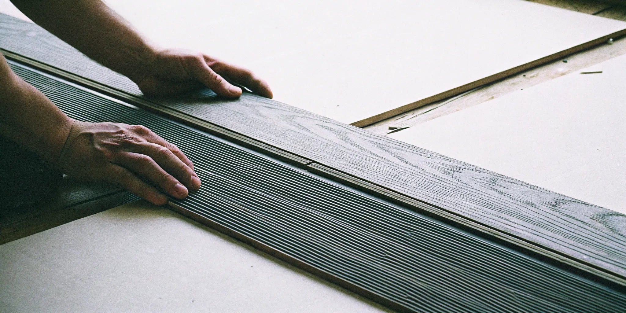 Applying wood glue to the joints of engineered wood flooring for a stable installation.