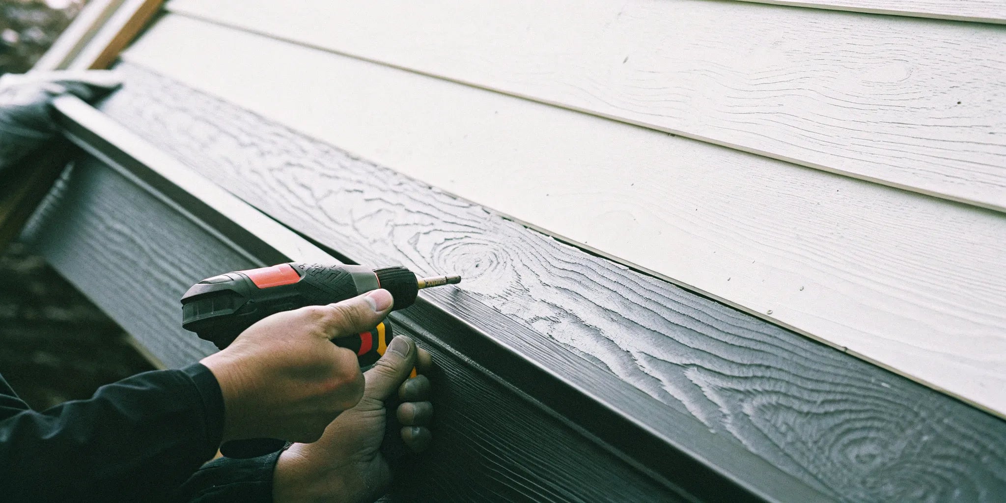 Installing WPC exterior wall cladding with a drill.
