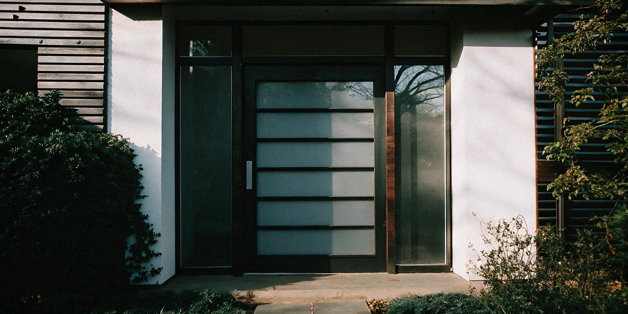 Mid-century modern steel entry door with frosted glass panels and clean geometric lines.
