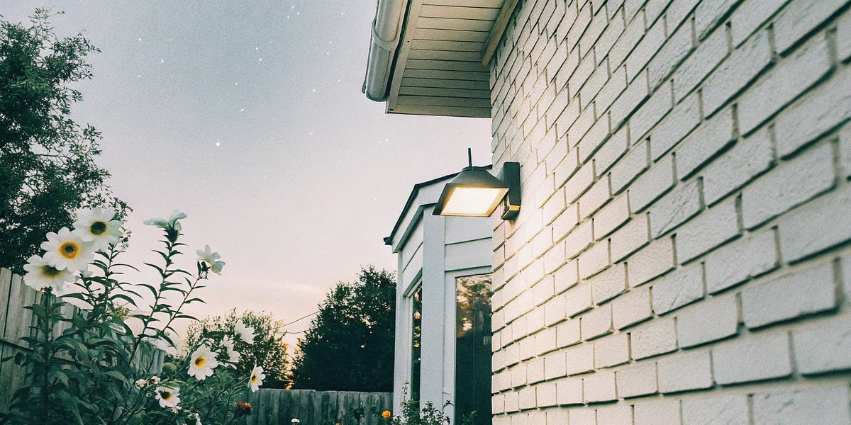 Outdoor wall sconce light mounted on a brick house for entryway lighting.
