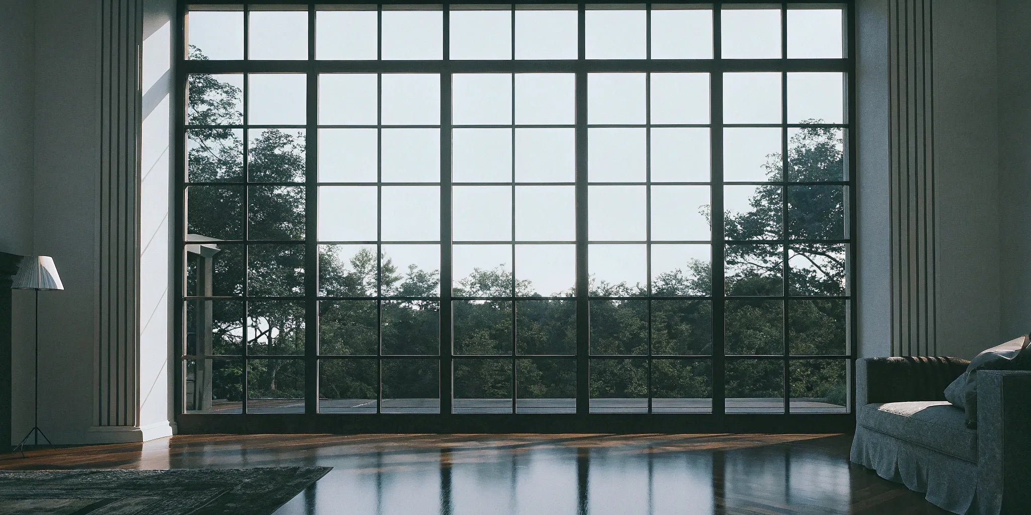 Large black steel casement windows flooding a room with natural light and a view of trees.