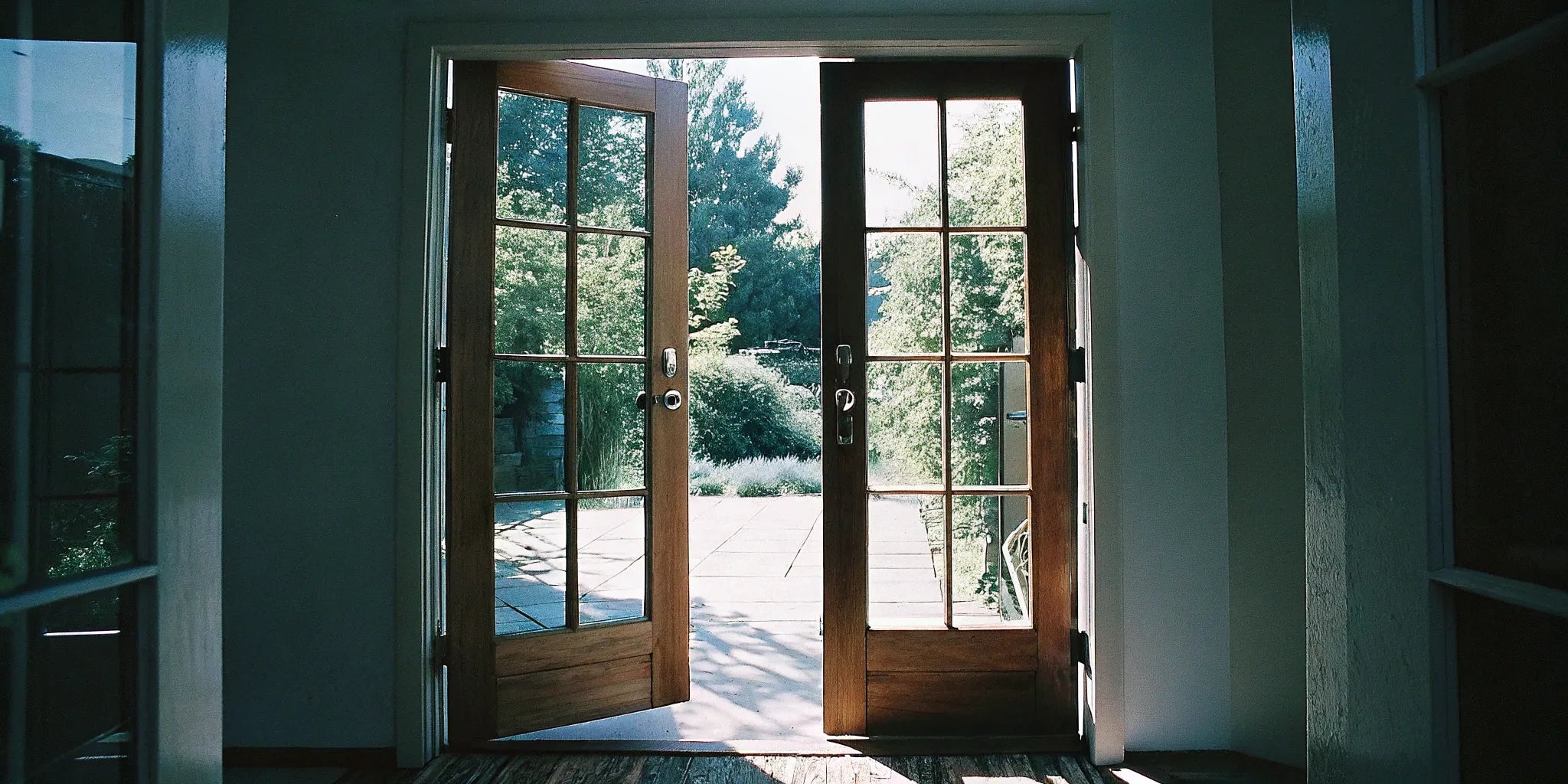 Prehung exterior outswing double doors with wood frames and glass panels.