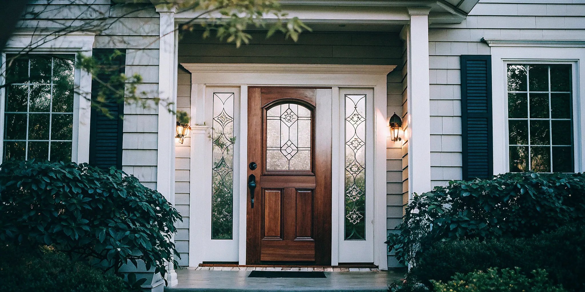 A classic wood front door with two sidelights and decorative glass panels.