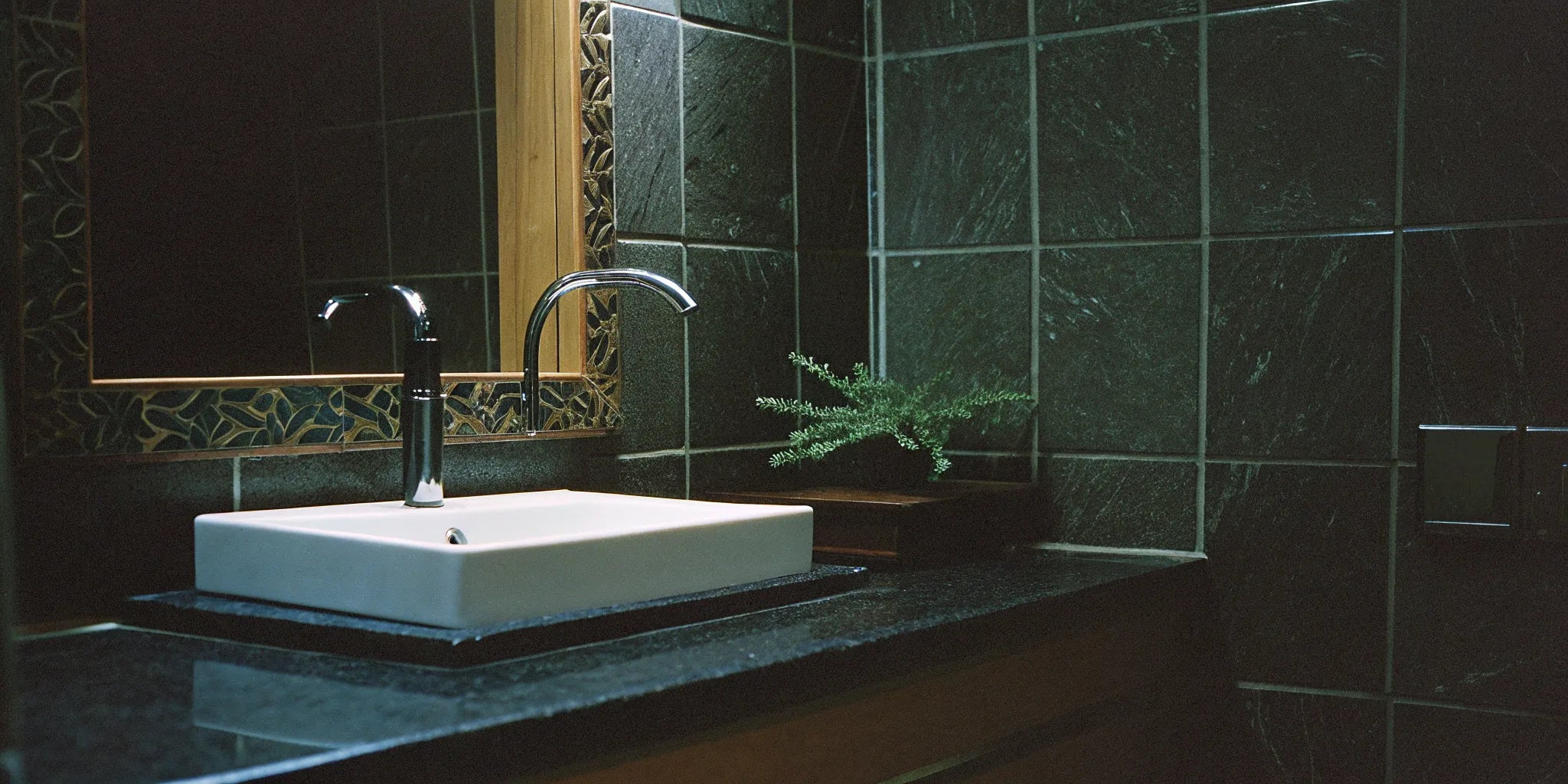 Dark porcelain slabs for walls create a seamless, modern look in this bathroom with a white sink.