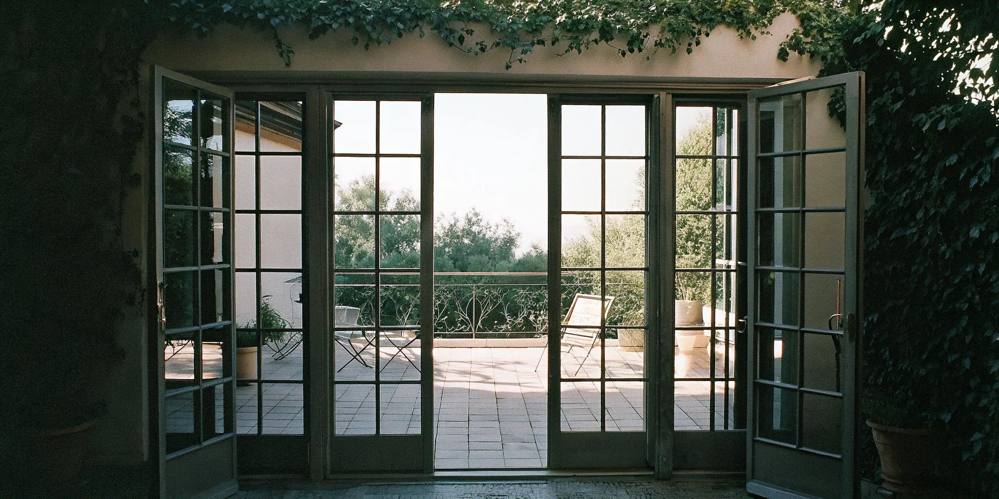 A pair of exterior metal French doors for sale opening onto a furnished patio.