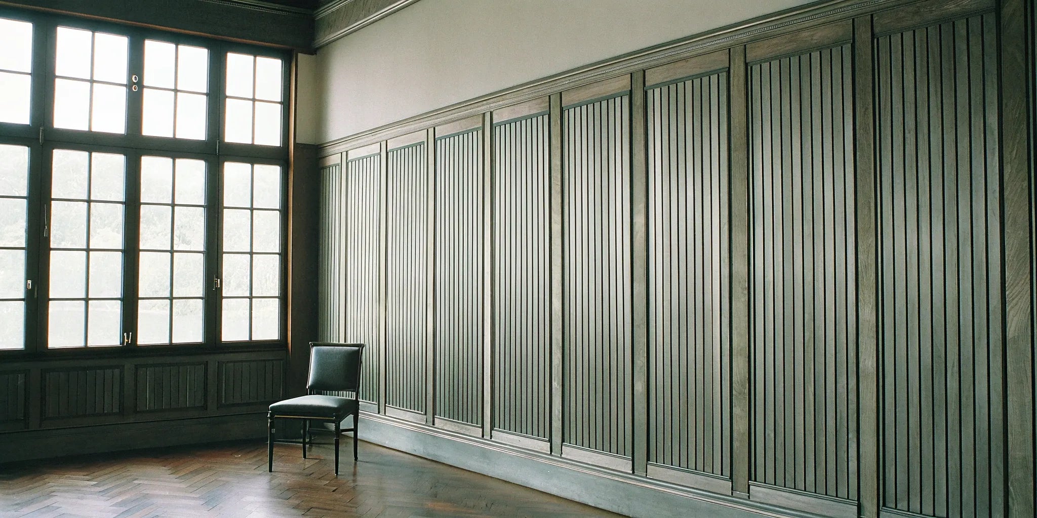 Flexible fluted wood panels creating a modern accent wall behind a single chair.