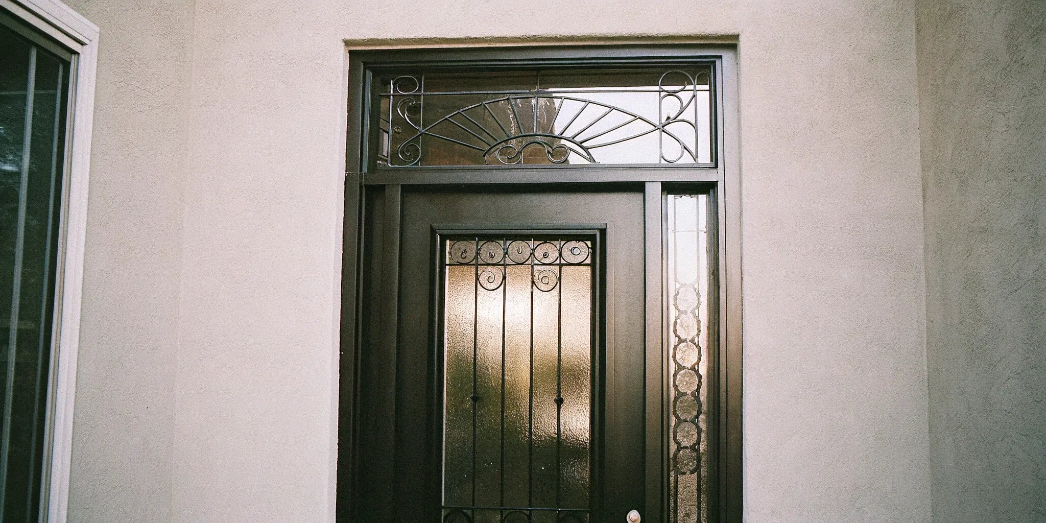 Black steel front door with decorative glass sidelights and a transom.