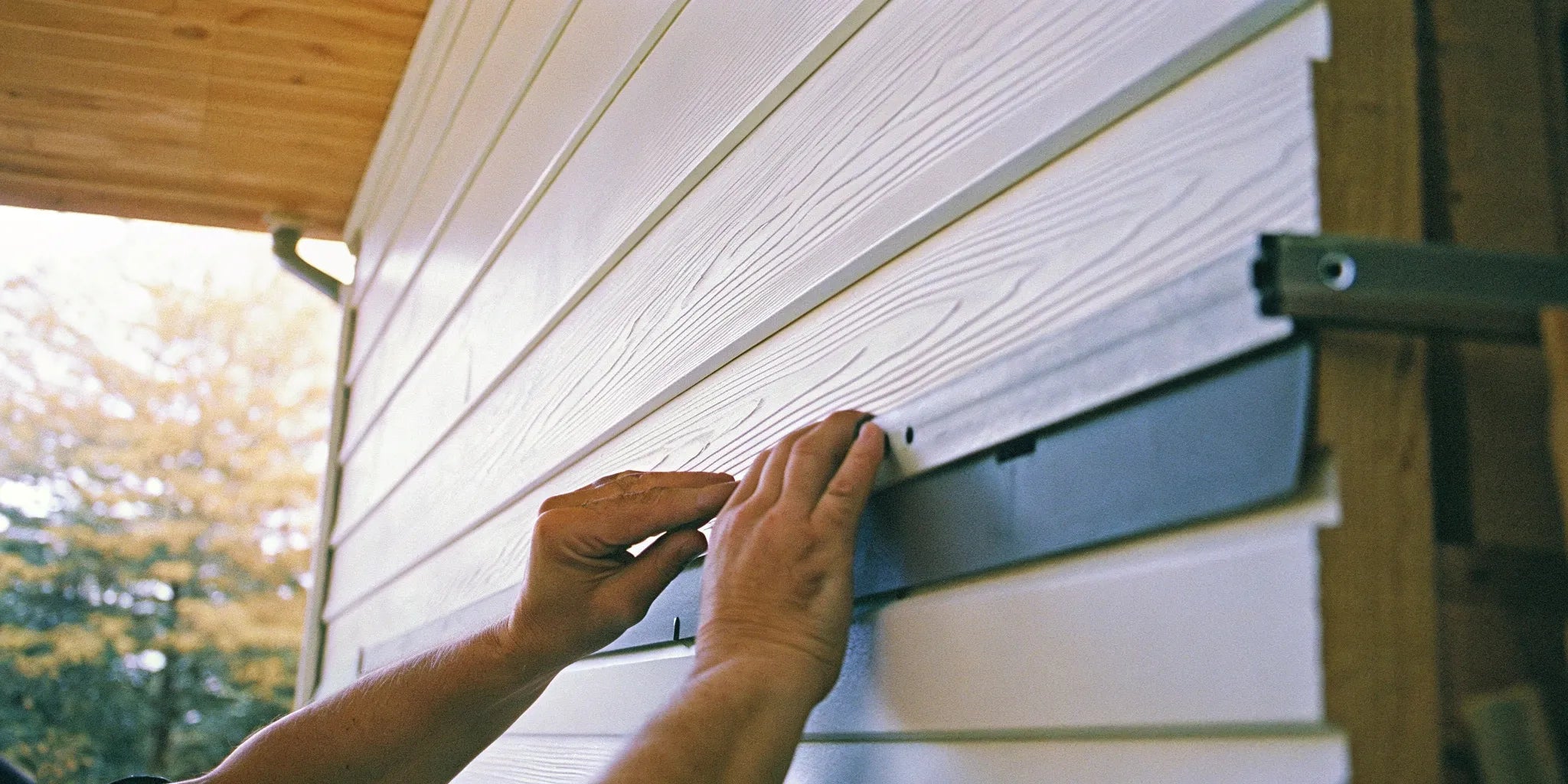 A person demonstrates how to install WPC wall cladding on an exterior wall.