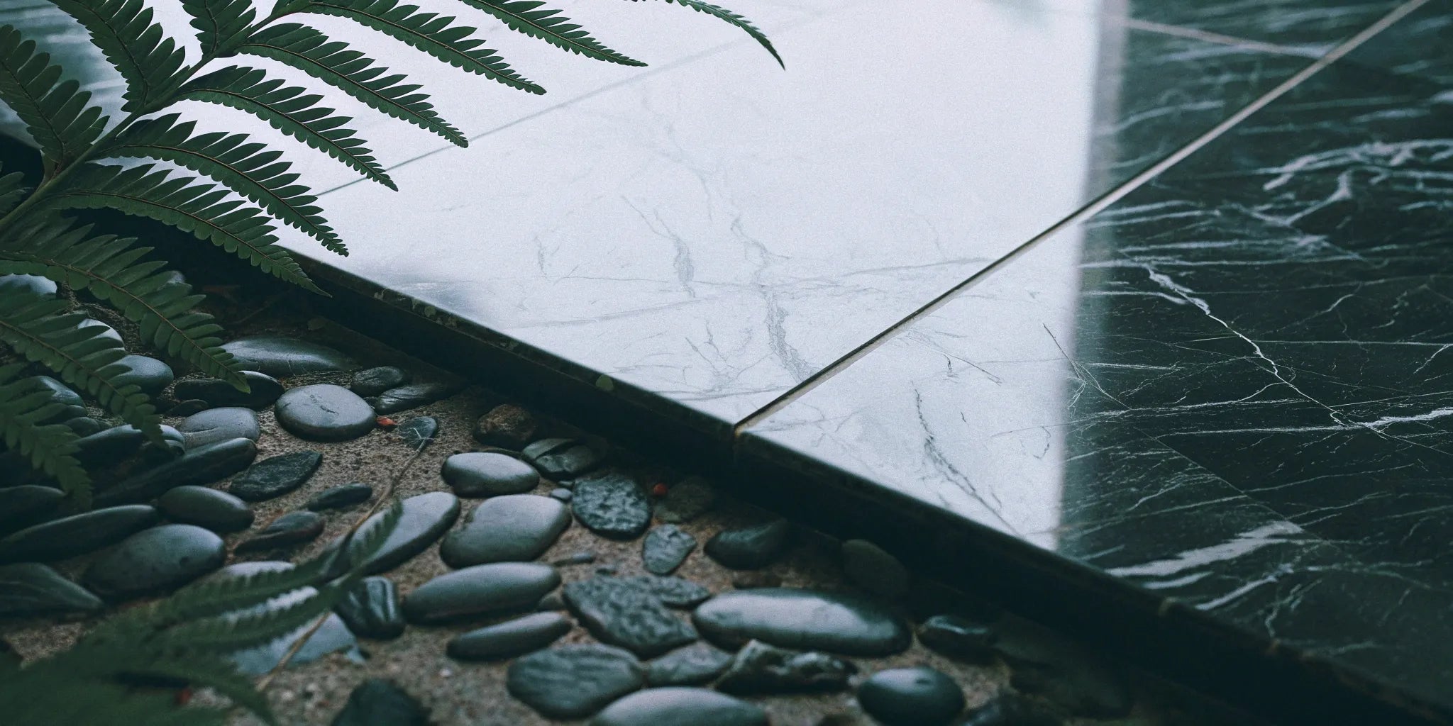 Marble-look porcelain tiles with dark pebbles and ferns.