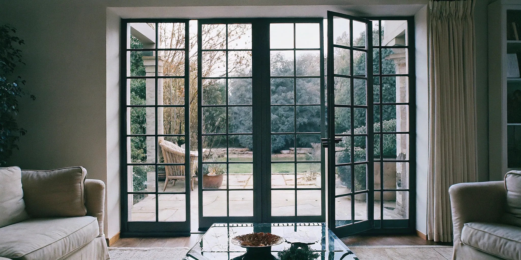 Black interior steel French doors with glass panels used as a modern room divider.