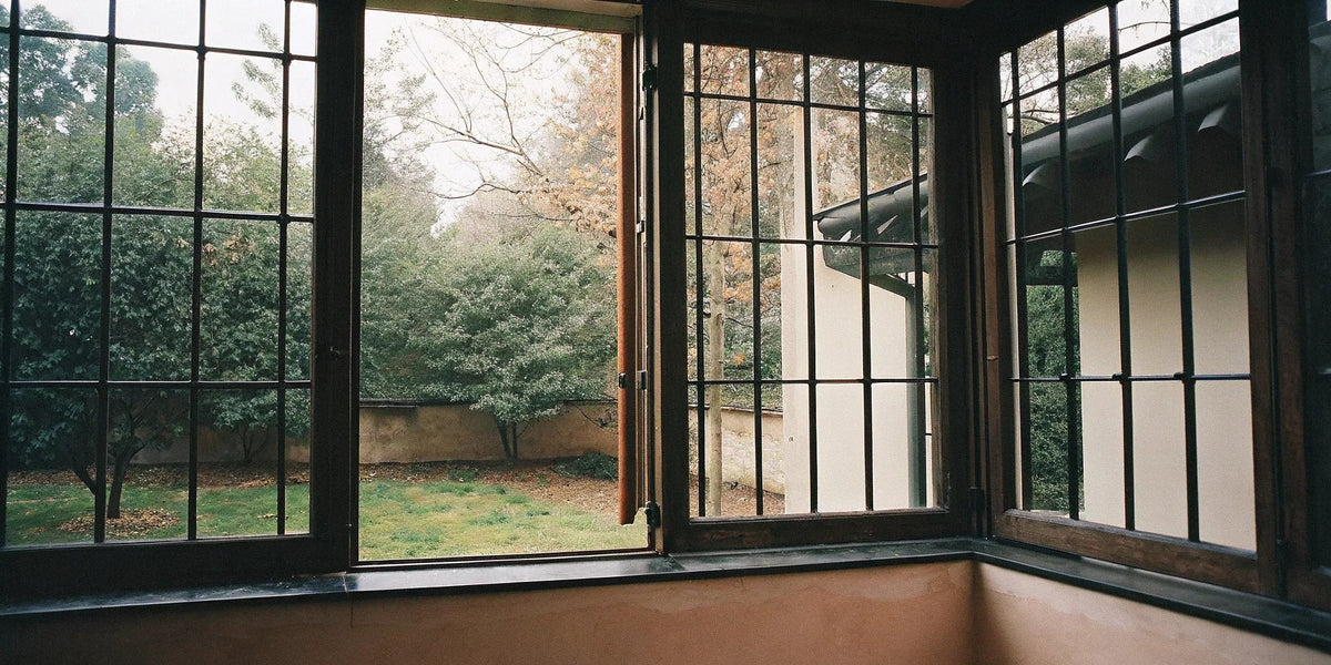 Modern black steel casement windows with slim frames open to a green backyard.