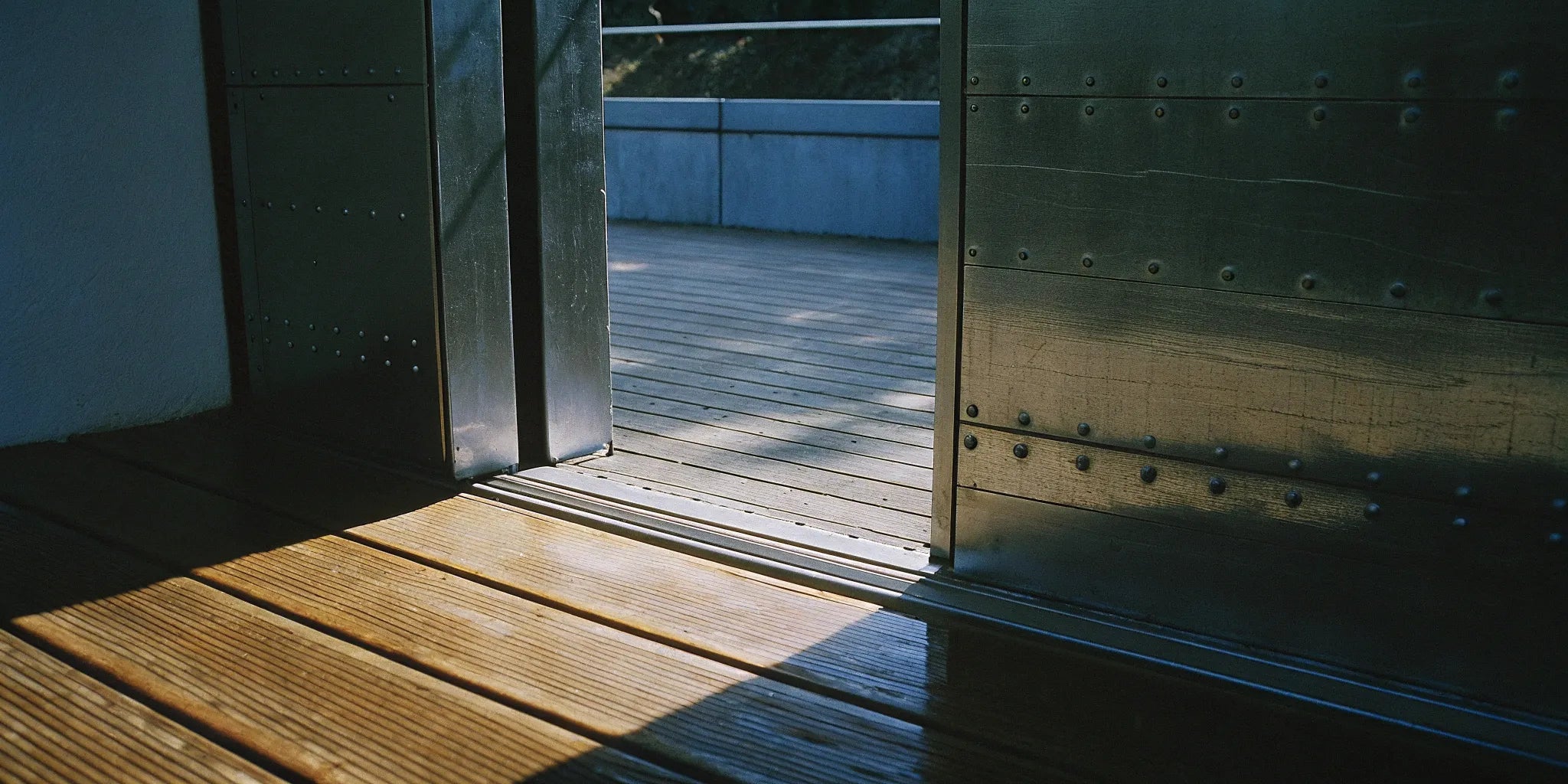 A modern 32x96 single steel door installed on a home, leading to a wooden deck.