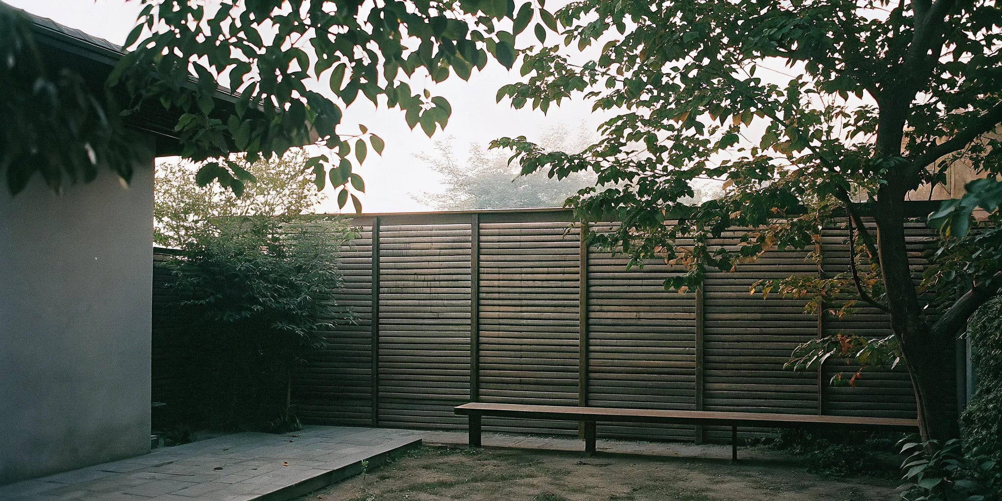 Vertical wood slat wall panel used as a privacy screen on a modern outdoor patio with a bench.