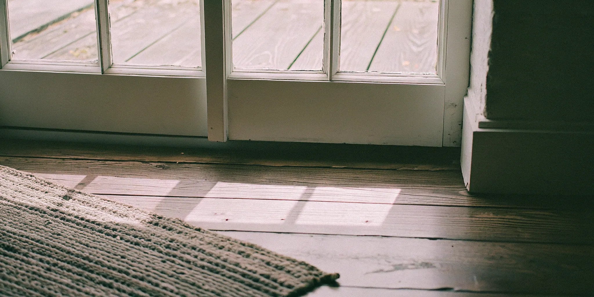 Farmhouse wide plank wood flooring with natural light and a textured rug.