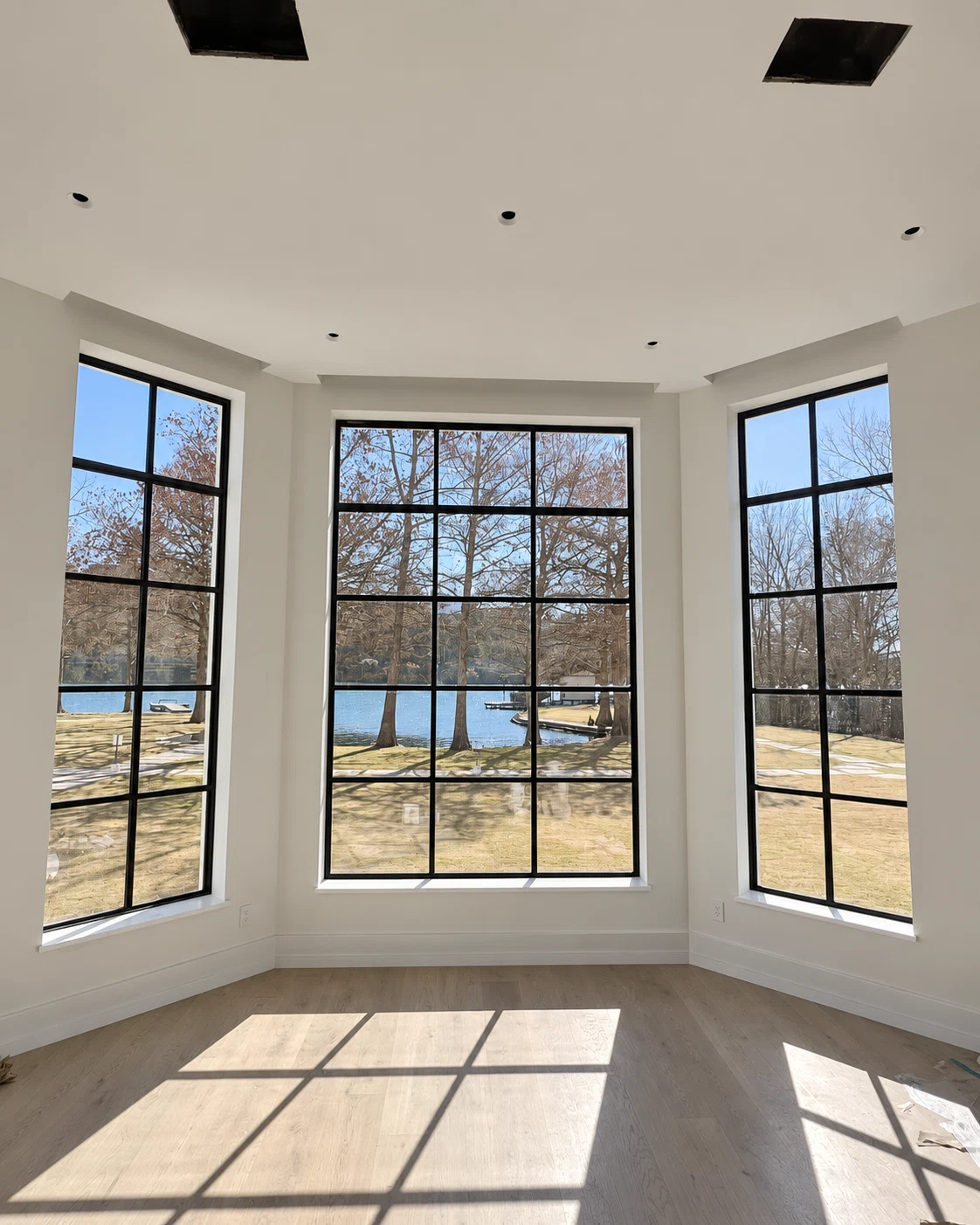 Steel windows installed by USABD overlooking a lake; interior finishing in progress